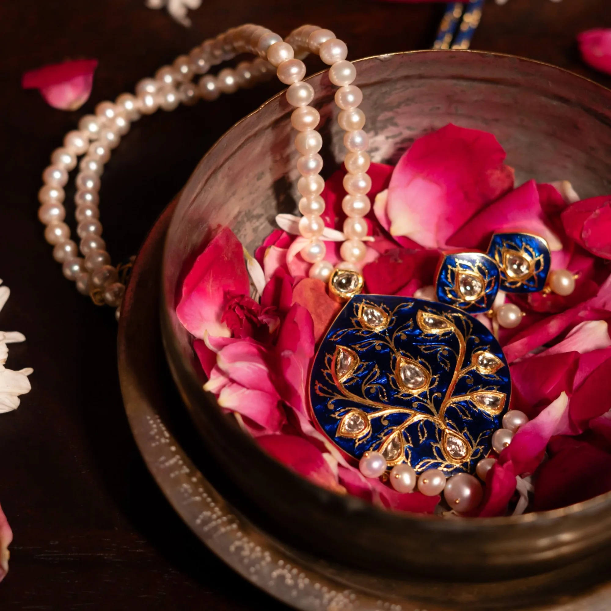 Jadau pendant with kundan and enamel resting on rose petals